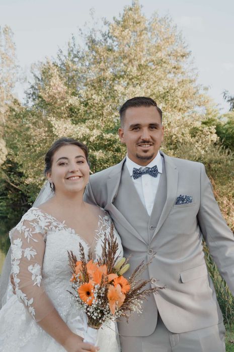 Couple de mariés avec bouquet orange en extérieur