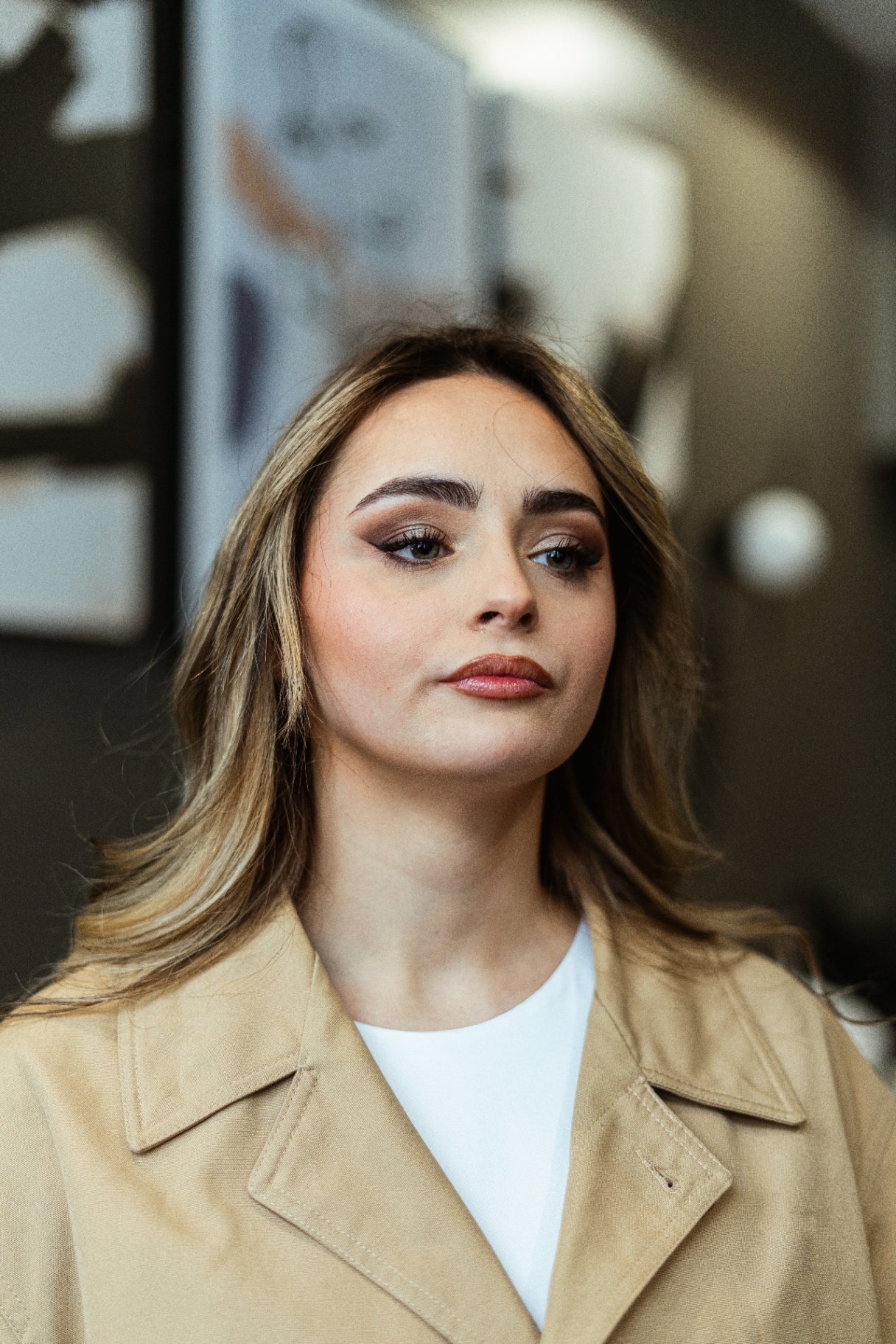 Maquillage smoky et bouche glossy sur trench beige